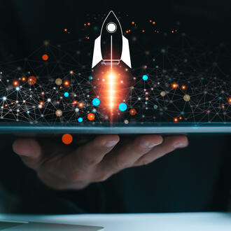 A business person uses a tablet is shown with a rocket symbol blasting off and shooting out of the screen with ai imagery